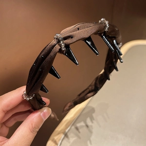 Detail of satin pleats and rhinestones on a dark brown headband with inner comb teeth