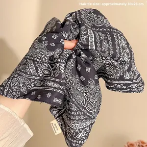 Detail view of navy paisley oversized scrunchie showing the handmade label and 30x23cm size