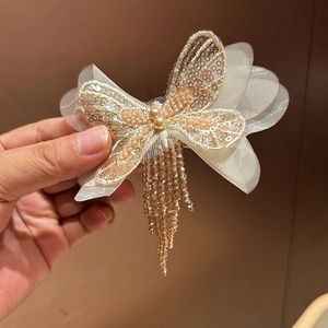 Détail d'une pince à cheveux papillon en résille champagne avec perles et franges