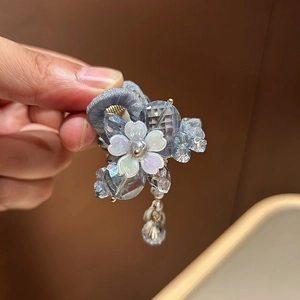 Détail de la pince à cheveux avec pompon en cristal pétales colorés et perles bleues