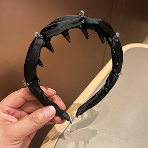 Detail of a black satin pleated headband with sparkling rhinestones and styling clips