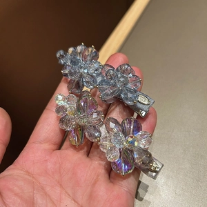 Detailed close-up of two sparkling floral rhinestone hair clips with iridescent beads