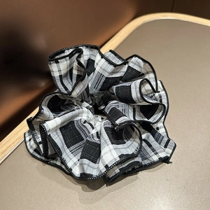 Classic black and white gingham scrunchie with pleated ruffles on a beige background