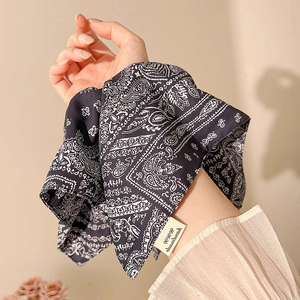 Detail of navy blue paisley print scarf wrapped around the wrist as a stylish accessory