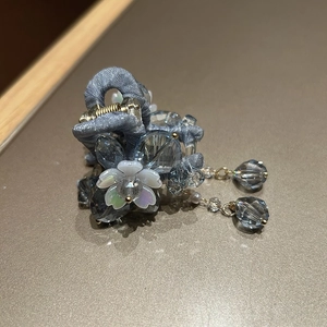 Détail de la pince à cheveux bleu-gris avec pompon en cristal et fleur blanche