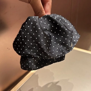 Detailed close-up of a French style black satin hair claw with white polka dot patterns