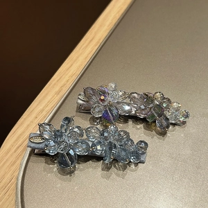 Detail of two handmade floral hair clips with crystal beads on a golden metal tray