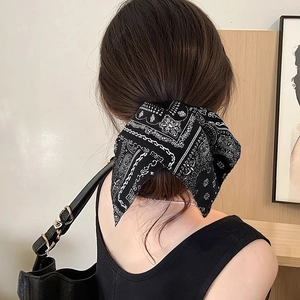 Detail of navy paisley bow hair tie styled on a low ponytail for a vintage look