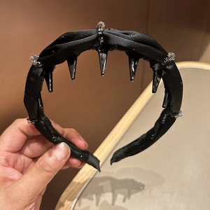 Detailed view of black satin headband with clear crystals and punk spikes texture