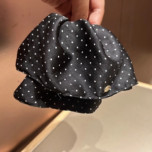 Elegant black satin polka dot hair clip with a small round gold metal emblem detail
