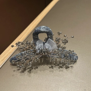 Detail of blue fabric hair claw clip with organza bow and intricate grey crystal beads