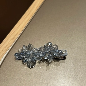Detailed view of beaded blue floral hair clip with crystal accents and silver metal base