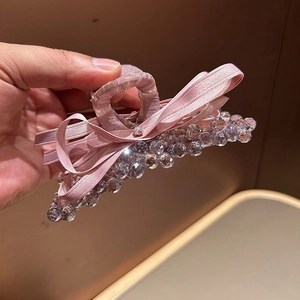 Close-up of pink ribbon bow hair claw with sparkling crystal beads and elegant design