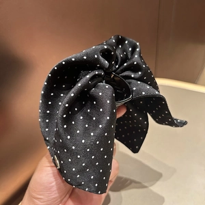Detail of large black and white polka dot satin bow hair claw with elegant texture