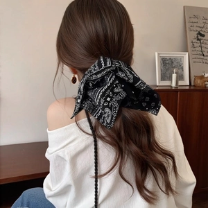 Close-up of navy blue paisley print bow hair scrunchie worn on a model's hair