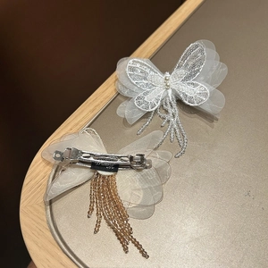 Détail de la pince à cheveux papillon avec ailes en maille blanche, paillettes et perles