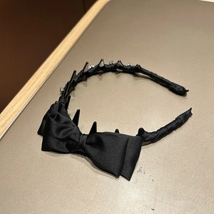 Detail of black satin bow headband with gothic-style spikes and sparkling rhinestones