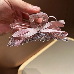 Detail view of pink satin bow hair claw clip decorated with crystal beads and beads