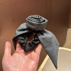 Detailed view of handmade grey striped fabric rose hair tie held in hand