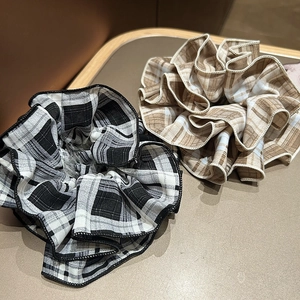 Detailed texture of black and brown plaid fabric scrunchies with soft pleats