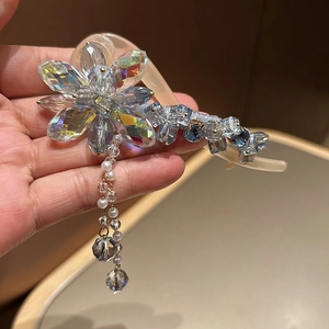 Détail d'une pince à cheveux fleurie en cristal avec pompons en perles et perles irisées
