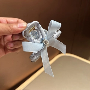 Detail of light blue satin bow hair claw with pearl and rhinestone embellishments
