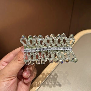 Macro detail of hand-woven crystal hair clip with square zircon center accents