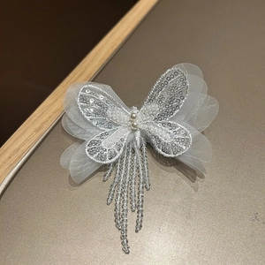 Détail de la pince papillon blanche avec paillettes argentées et glands en perles