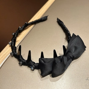 Detail of black satin headband featuring 3D bow, spiked hair claws, and sparkling rhinestones