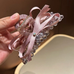 Detail of pink ribbon bow hair claw clip with sparkling crystal beads and golden spring