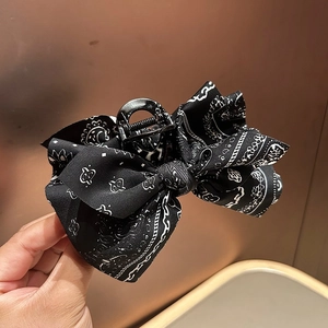 Detail of a large paisley bow hair claw clip in classic black and white print