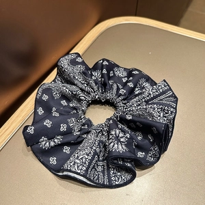 Detail of navy blue paisley print scrunchie with soft satin texture and neat stitching