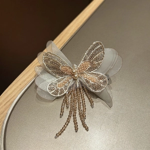 Détail d'une pince à cheveux papillon élégante avec paillettes et pompons perlés
