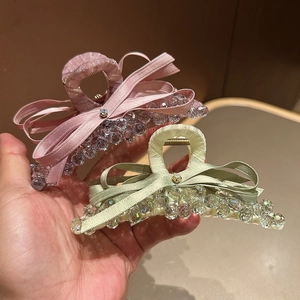 Close-up of pink and green bow hair claws with sparkling crystals and beaded fringe
