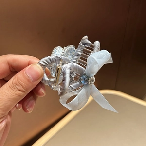 Detailed view of camellia hair claw clip with blue organza bow and pearl accents