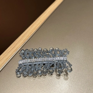 Detailed macro view of hand-woven blue crystal hair clip with baguette-cut zircons