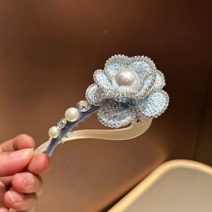 Detail of blue tweed camellia hair clip with shimmering rhinestones and large pearl inlay