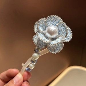 Detail of light blue tweed flower clip with pearl center and rhinestone trim