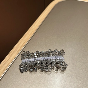 Macro detail of hand-woven grey crystals and rectangular zircon on the metal hair clip