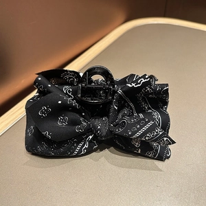 Detail of large claw clip featuring a black and white paisley print fabric bow accessory
