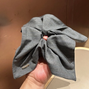 Detail of grey striped fabric hair scrunchie with metallic logo tag and elegant texture
