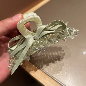 Detailed view of the mint green satin bow hair claw clip with sparkling crystal accents