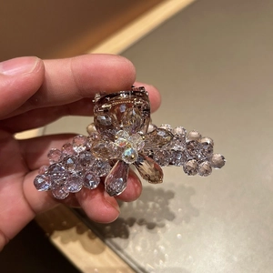 Détail macro de cristaux tissés main et strass champagne sur un bandeau métallique