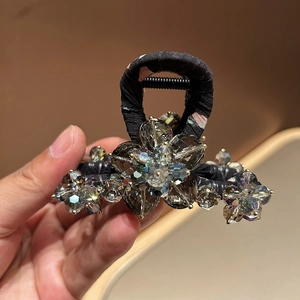 Detail shot of black floral fabric hair claw clip with sparkling crystal flower clusters
