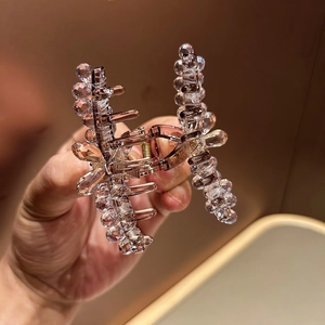 Détail d'une pince à cheveux en cristal avec des perles violettes et un ressort en métal