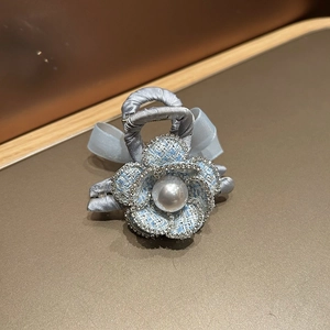 Close-up of camellia hair clip with tweed fabric petals, rhinestones and center pearl