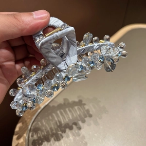 Dettaglio di un grande fermaglio per capelli con cristalli blu e tessuto satin
