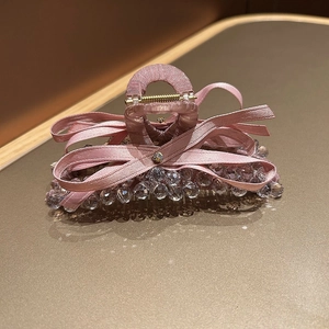 Detailed shot of pink satin bow hair claw with sparkling crystal beads and golden spring