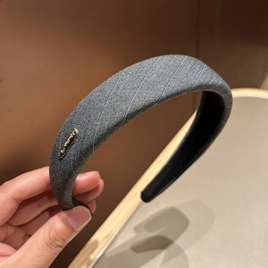 Detail of grey striped fabric headband with a luxury style metallic logo plate