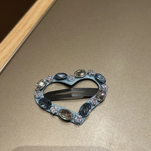 Macro detail of heart-shaped denim hair clip with embedded blue and clear gemstones